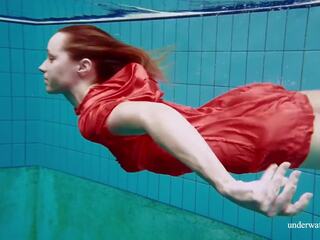Czerwony długo sukienka i duży cycki floating w the basen